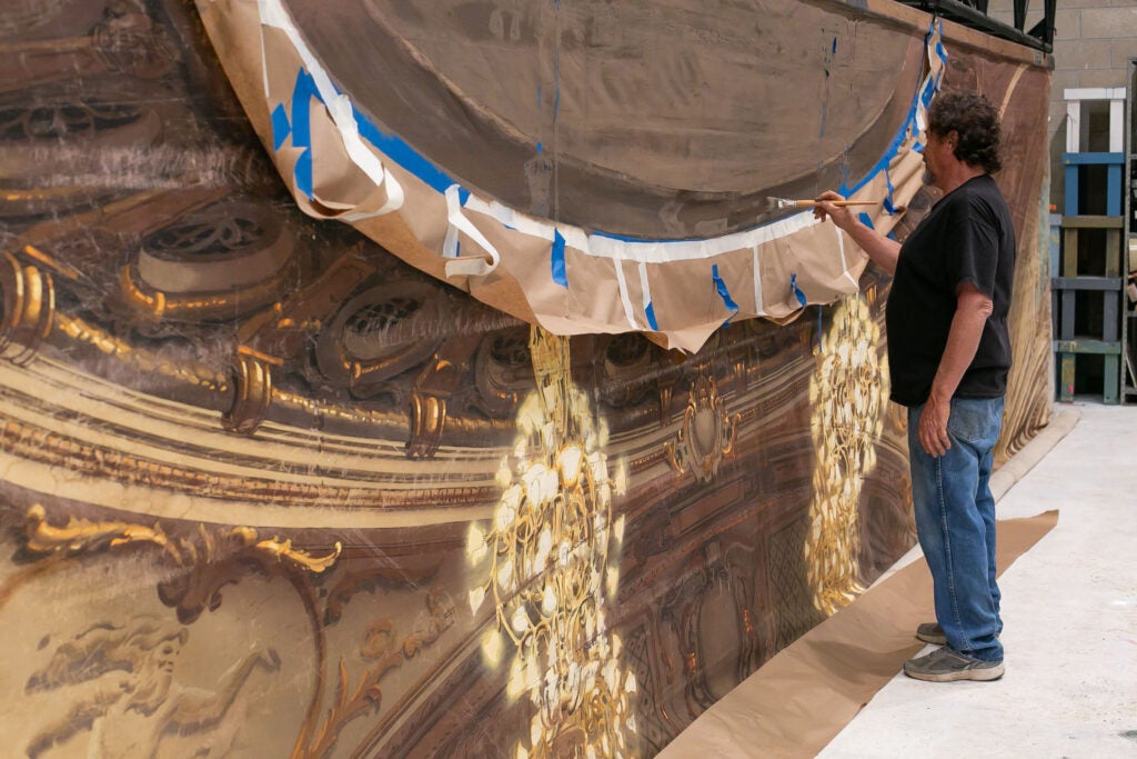 Michael Denering 2023 (Top), Joe Francuz (Bottom Lt.), and student Isabella Hollis preserve The Law and the Lady (1951) backdrop at the Texas Performing Arts Fabrication Studios. (Bottom Rt.)